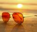 red lens sunglasses on sand near sea at sunset selective focus photography